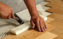 Applying adhesive for wood floor installation