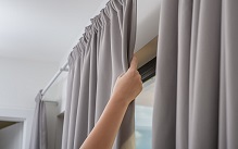 Hand-adjusting-gray-curtain-on-rod