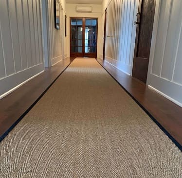 Herringbone sisal runner rug in wooden hallway