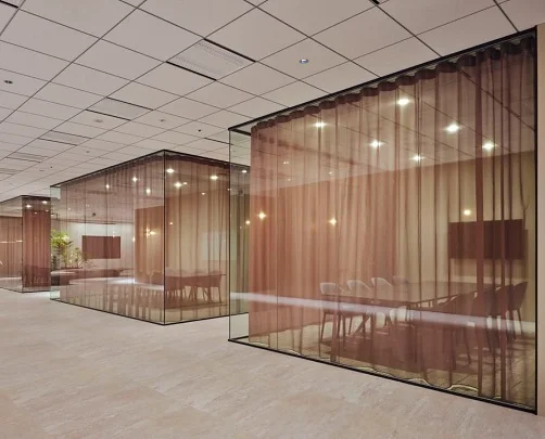 Glass meeting rooms with sheer bronze curtains